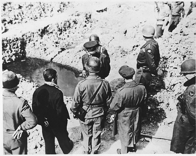High-ranking U.S. Army officers examine a mass grave in the newly liberated Ohrdruf concentration camp. Among those pictured are Generals Dwight D. Eisenhower, George Patton, Omar Bradley and Manton Eddy. Also pictured is Jules Grad, correspondent for the U.S. Army newspaper, "Stars and Stripes"