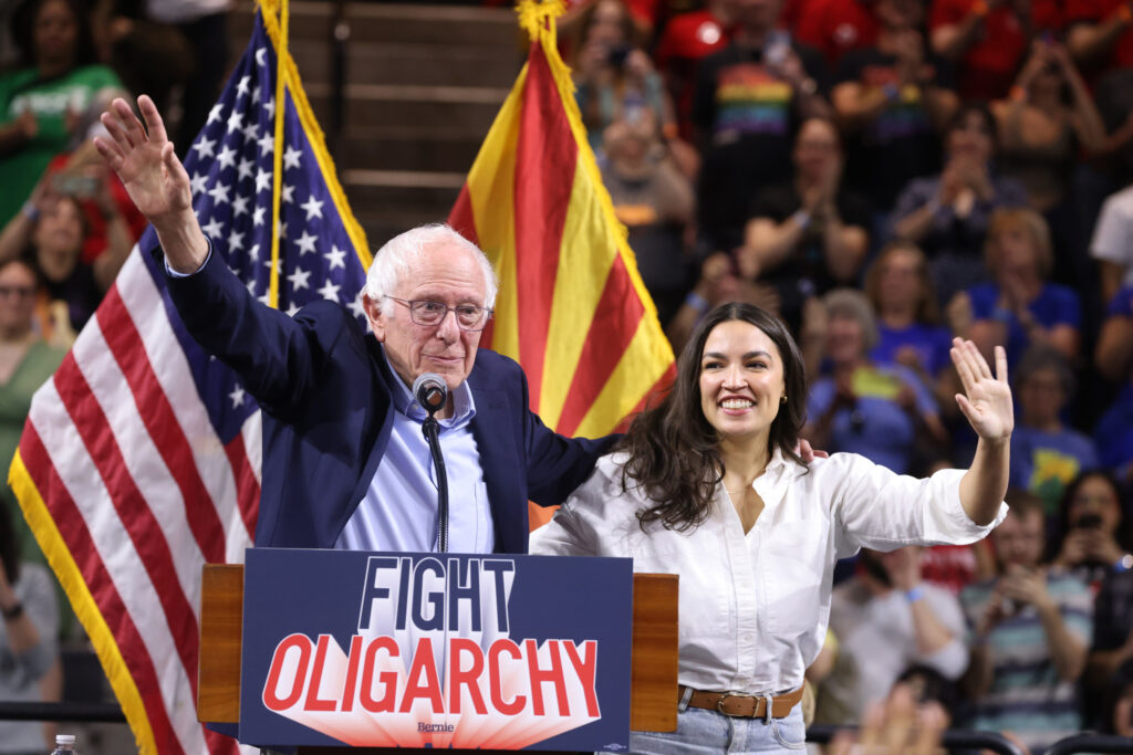 U.S. Senator Bernie Sanders and U.S. Congresswoman Alexandria Ocasio-Cortez speaking with attendees at a "Fight Oligarchy" rally at Mullett Arena in Tempe, Arizona. March 20, 2025. Credit Gage Skidmore. Via Flickr