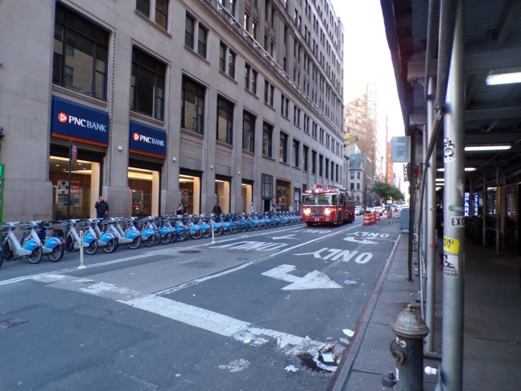 A view of West 31st Street in Manhattan, NYC of a citibike dock and a fire engine on its way to a call.